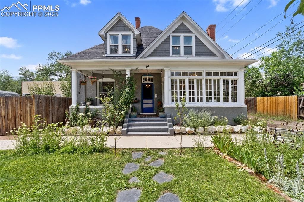 View of front of home with a chimney, a porch, and a shingled roof