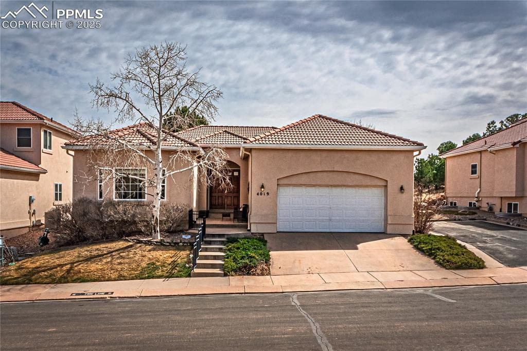 Mediterranean / spanish home featuring driveway, a garage, a tiled roof, and stucco siding
