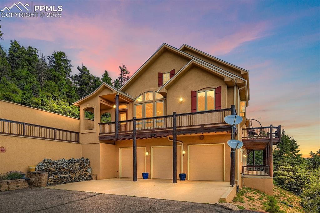 View of front facade featuring stucco siding, a patio, driveway, and a garage