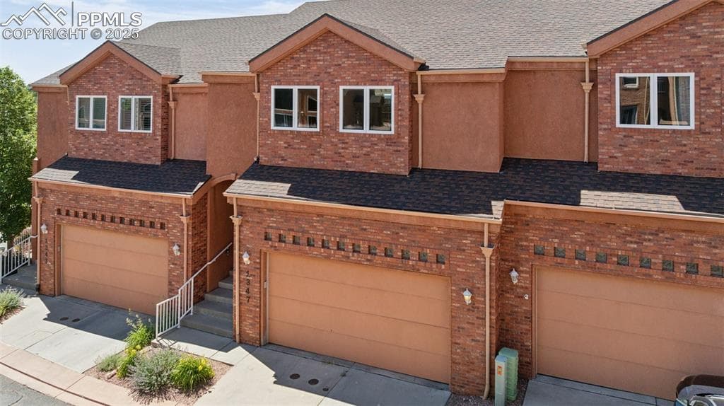 View of front facade with an attached garage, brick siding, driveway, and roof with shingles