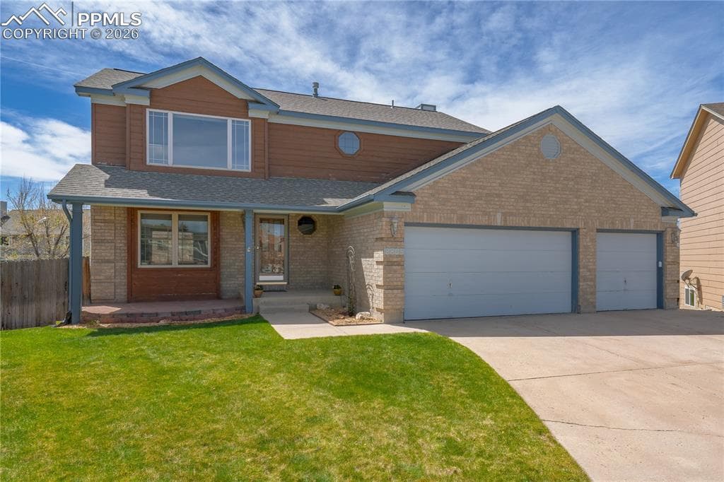 The property features a two-story design with a brick and wood-paneled exterior, a covered front porch, and a concrete driveway leading to a three-car garage