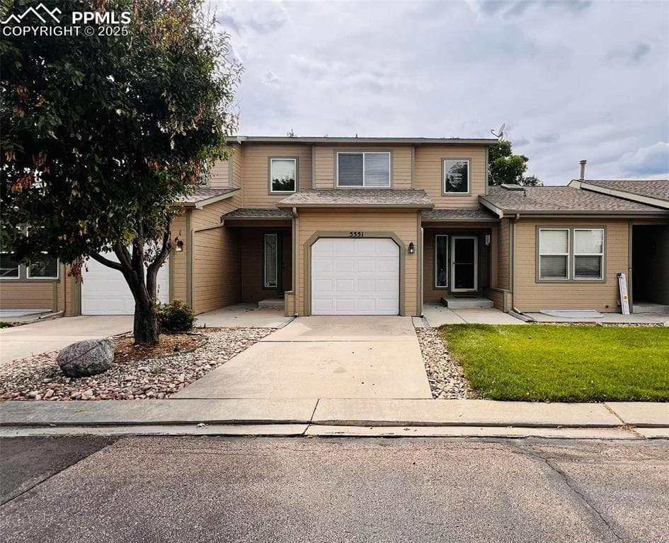 Traditional-style house featuring driveway, a shingled roof, and a garage