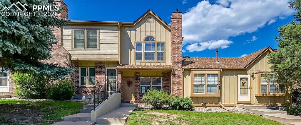 View of front of property featuring brick siding, a chimney, and a front lawn