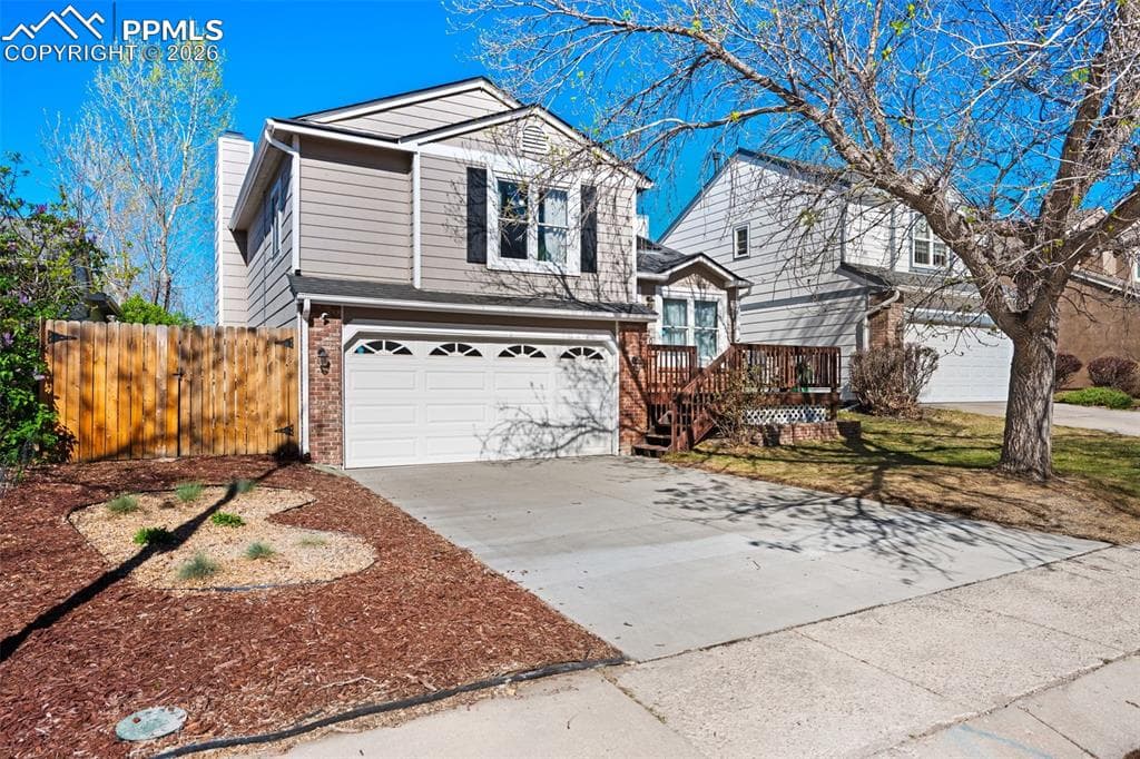 The property features a two-car garage, a concrete driveway, and a front yard with bark mulch landscaping
