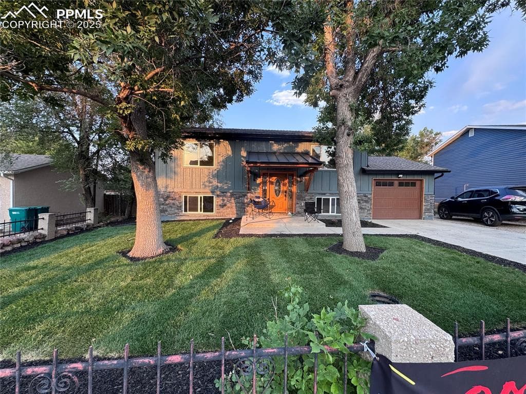 View of front of house featuring stone siding, concrete driveway, a garage, and board and batten siding