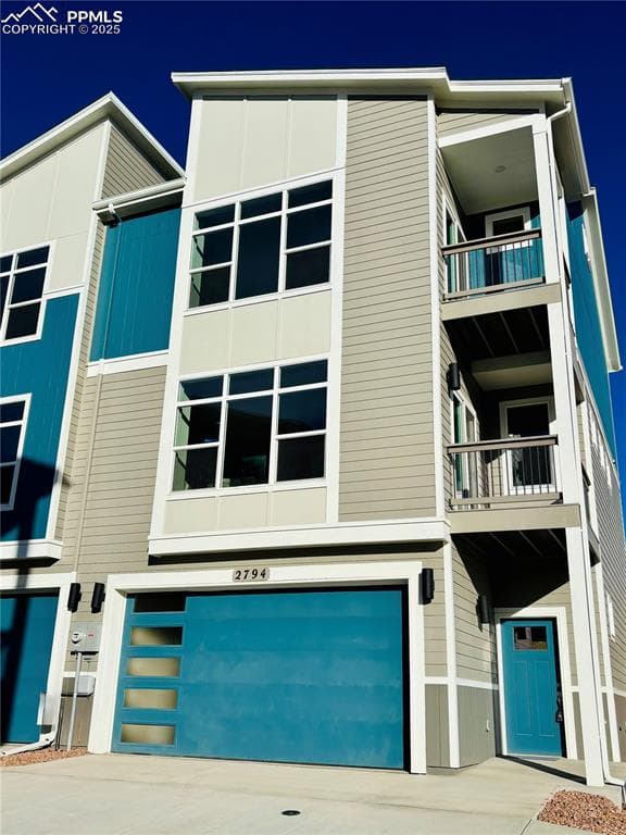 View of front of property featuring a garage, a balcony, and concrete driveway