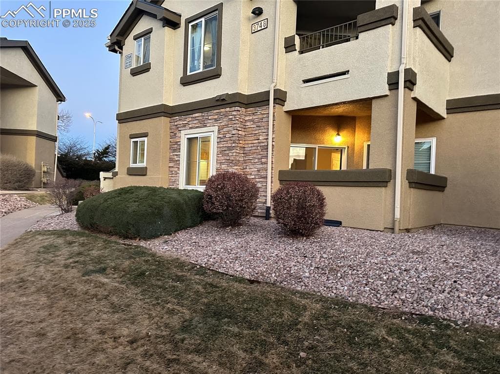 View of home's exterior with stone siding, stucco siding, and a balcony